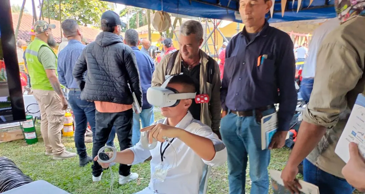 Trabajadores prueban el simulador de realidad virtual de motos en una feria de seguridad vial